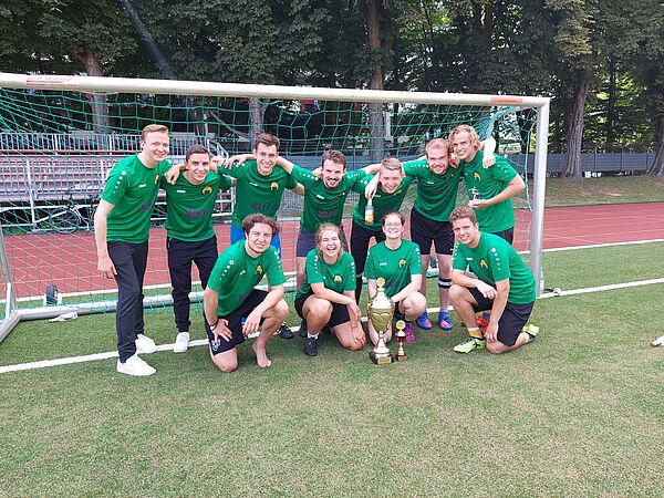 Die Mannschaft "Hals und Steinbrecher" vom Institut für Journalistik vor einem Fußballtor nach ihrem Sieg beim J-Cup 2022