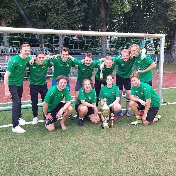 Die Mannschaft "Hals und Steinbrecher" vom Institut für Journalistik vor einem Fußballtor nach ihrem Sieg beim J-Cup 2022