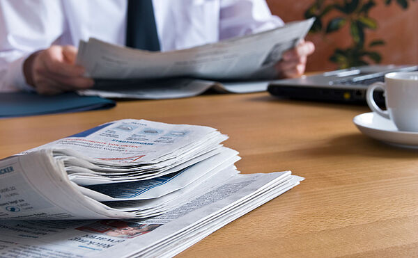 Ein Mann sitzt am Tisch und liest Zeitung