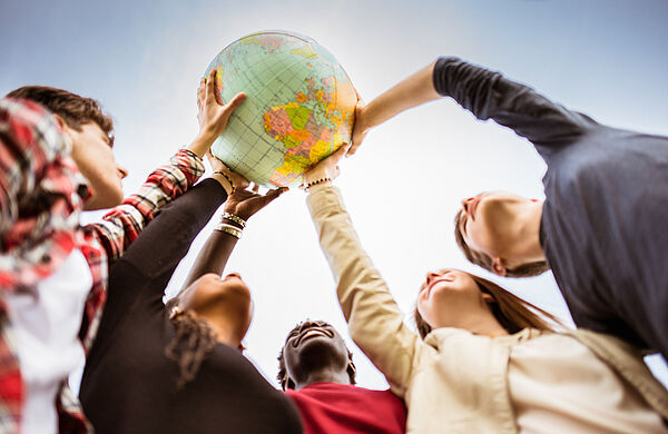 Junge Menschen halten gemeinsam einen Globus hoch
