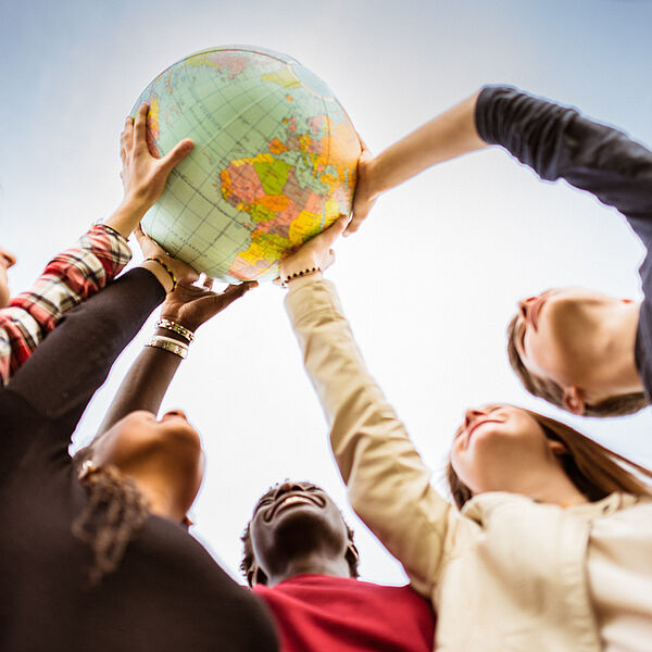 Junge Menschen halten gemeinsam einen Globus hoch
