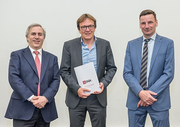 Ein Gruppenfoto mit Prof. Dr. Holger Thiele, Prof. Dr. Ulf Landmesser und Prof. Holger Wormer, der in der Mitte steht und die Urkunde hält. 