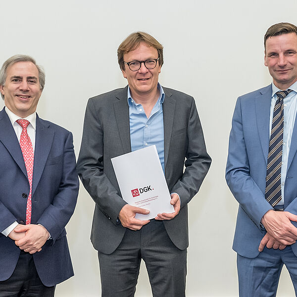 Ein Gruppenfoto mit Prof. Dr. Holger Thiele, Prof. Dr. Ulf Landmesser und Prof. Holger Wormer, der in der Mitte steht und die Urkunde hält. 