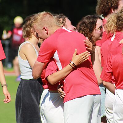 Spieler:innen, die sich nach dem Spiel auf dem Fußballplatz umarmen